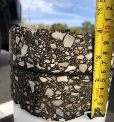 Ten inch thick road core being measured with tape measure